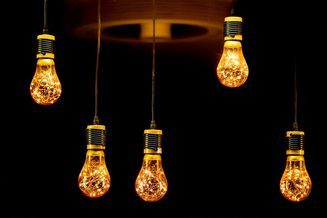 Five decorative edison bulbs hanging against black