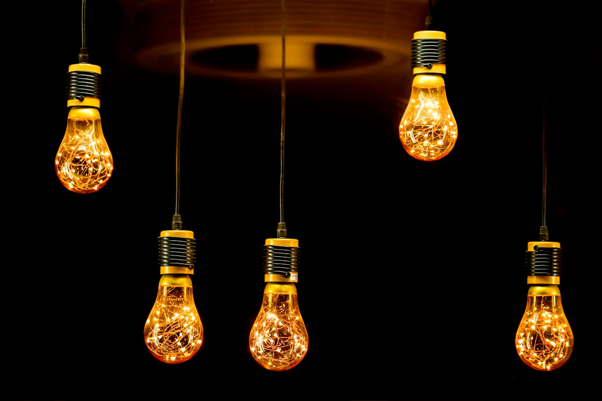 Five decorative edison bulbs hanging against black
